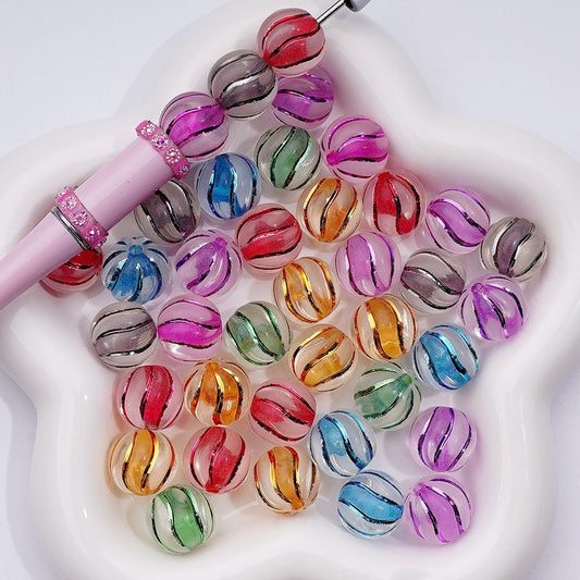 Colorful glass beads on a white surface with a pink tool.

