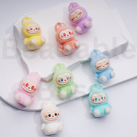 Set of colorful plush toys resembling babies on a white surface

