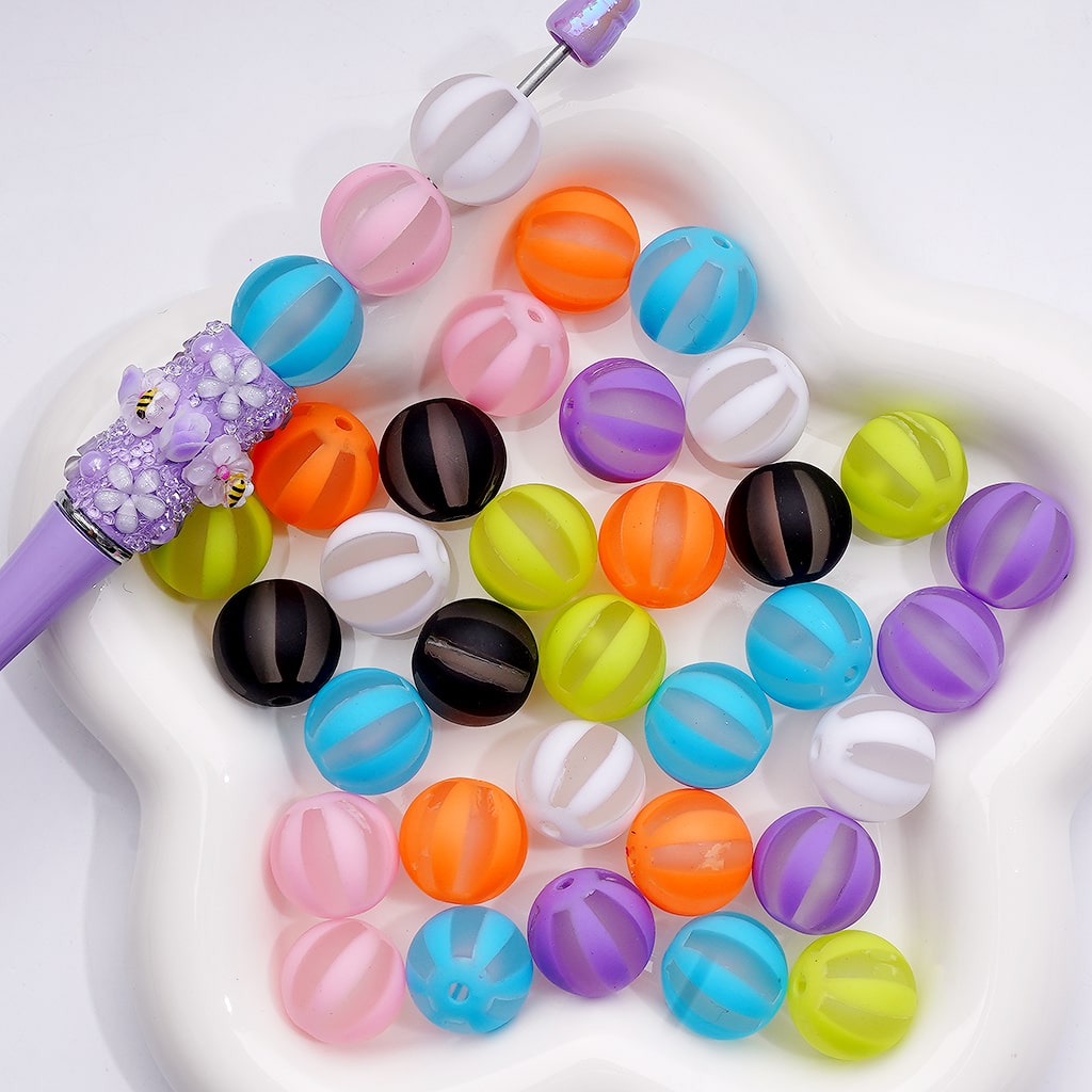 Colorful beads with a purple tool on a white background

