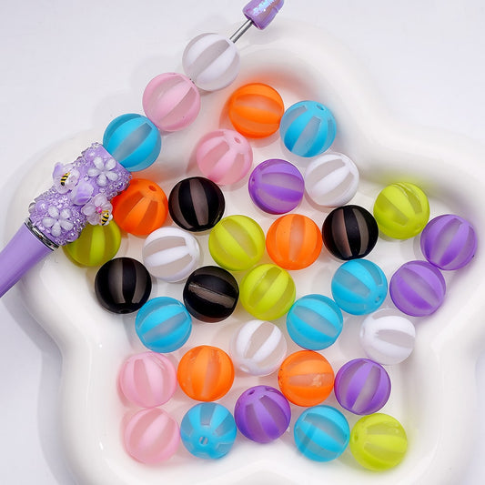 Colorful beads with a purple tool on a white background

