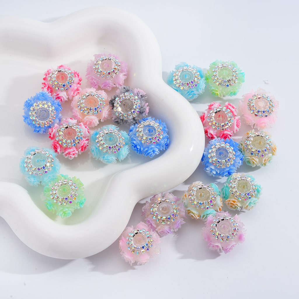 Decorative beads with rhinestones and fluffy textures on a white dish

