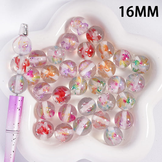 Decorative beads with floral patterns on a white surface, with a pink tool next to them.