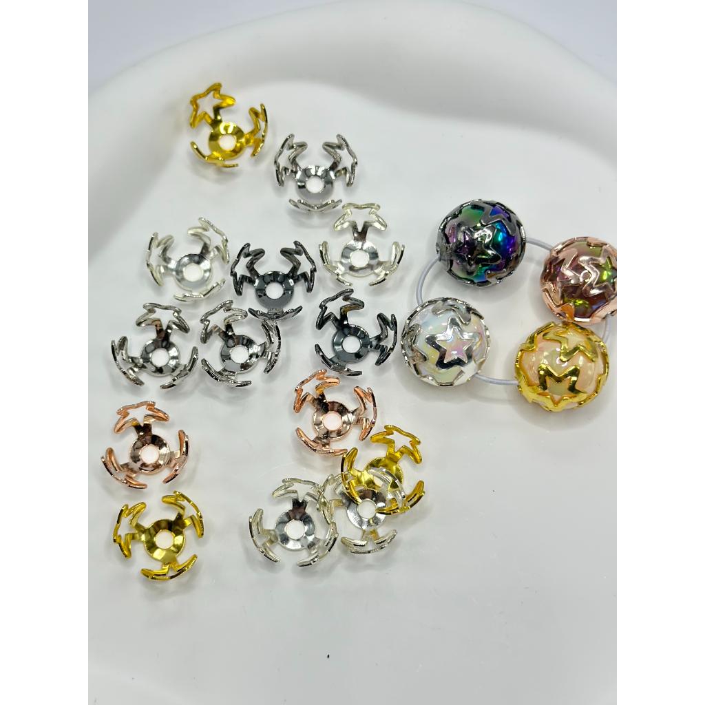 A collection of bead cap bead cages in silver, gold, and rose gold colors arranged on a white surface.


