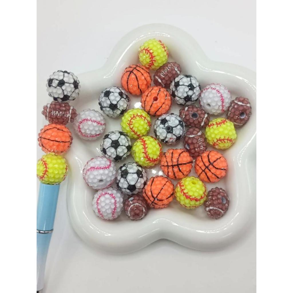 Assorted sports ball beads on a heart-shaped white dish

