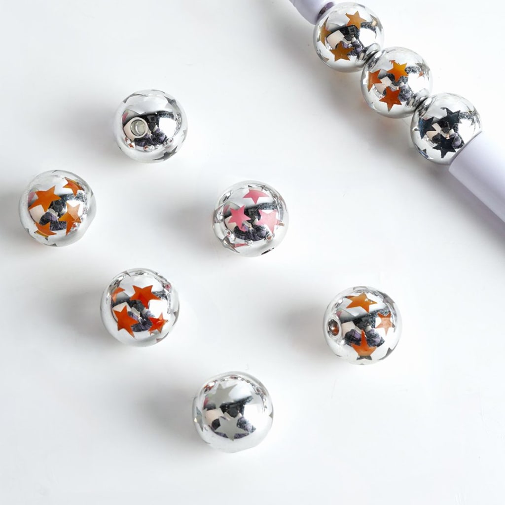 A collection of double layer star patterned acrylic beads in silver color with multicolored stars inside.

