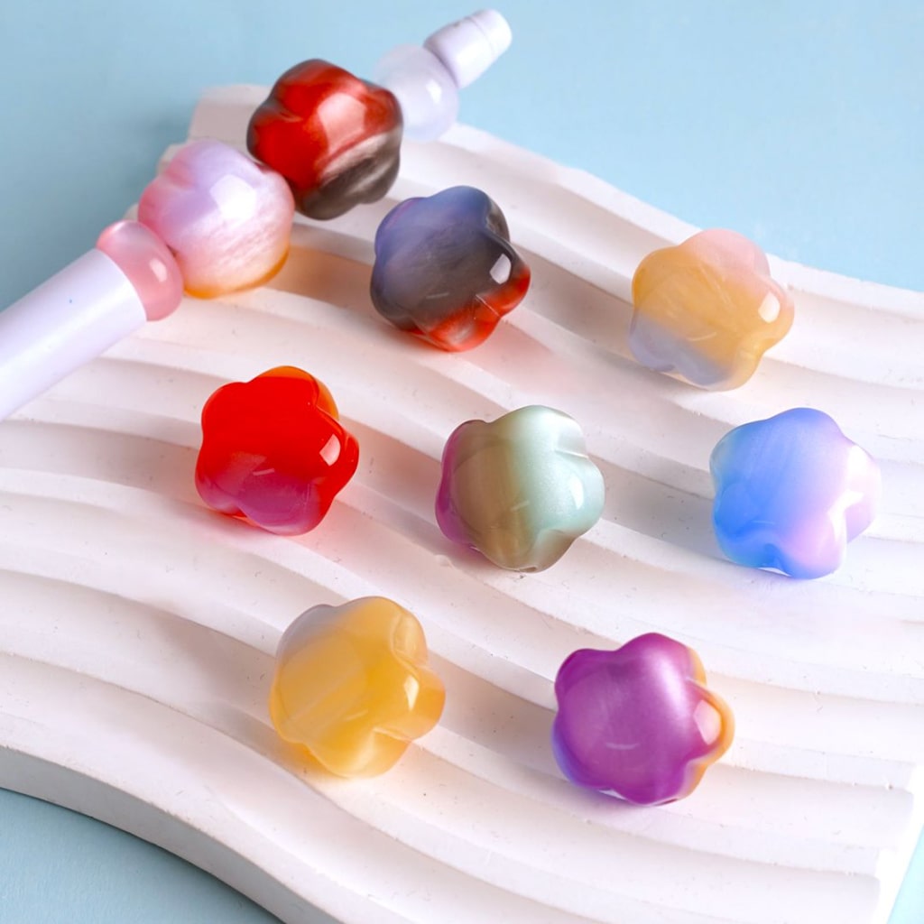 A collection of multicolored acrylic beads shaped like flowers, displayed on a white surface.

