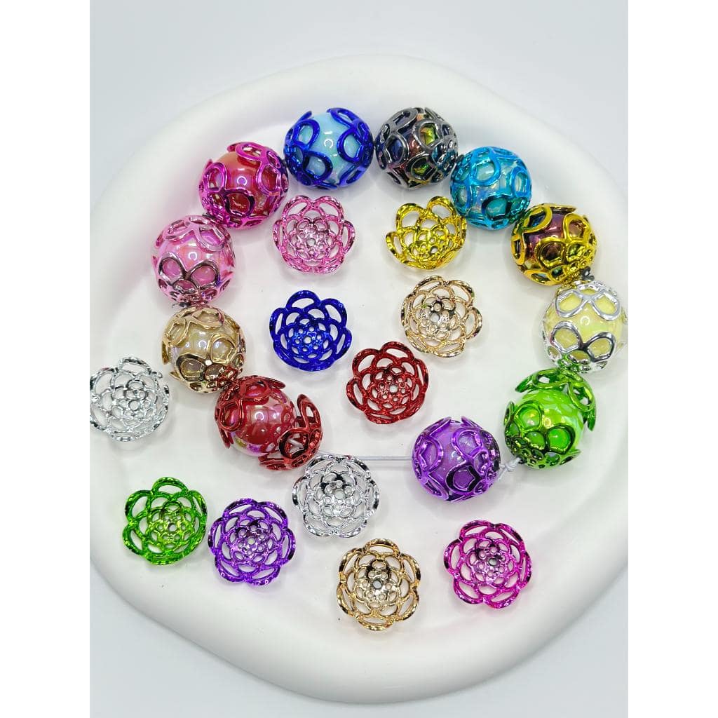 A collection of multicolored flower-shaped bead caps displayed on a white surface.

