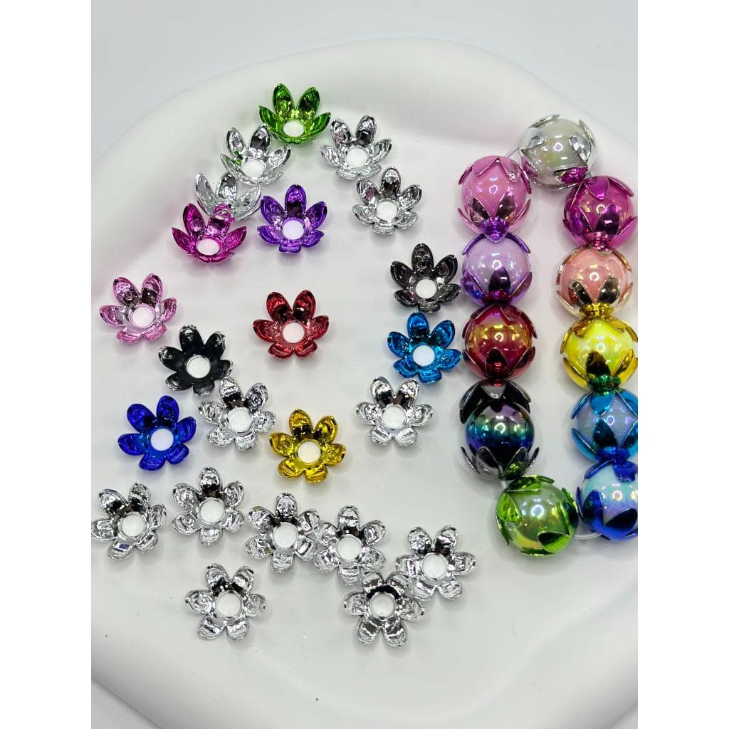 A collection of metallic colored floral bead caps displayed on a surface.

