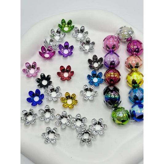 A collection of metallic colored floral bead caps displayed on a surface.

