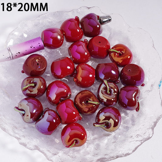 Red cherry-shaped beads on a white stone surface with a pink tool.