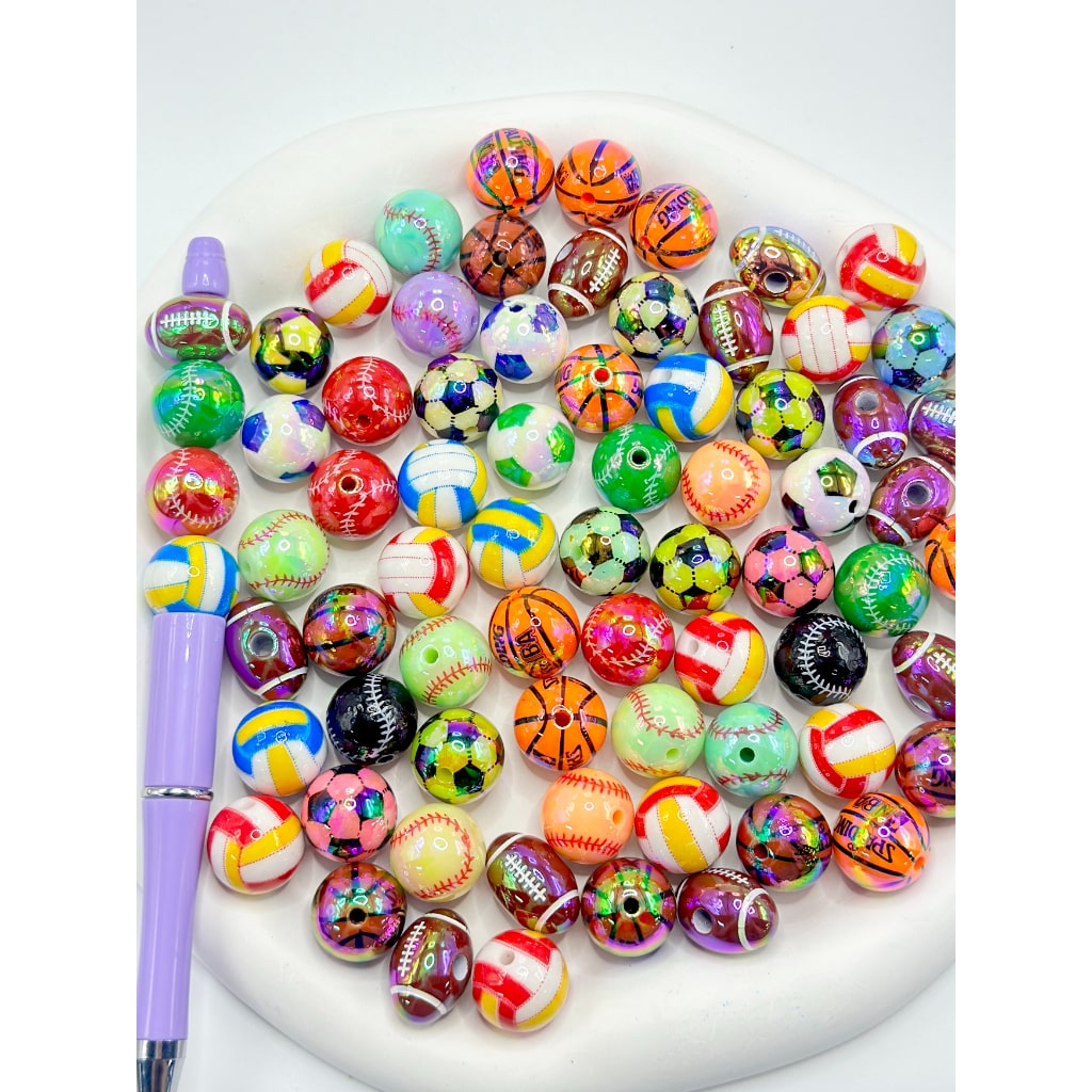 Assorted colorful beads on a white plate with a purple pen.


