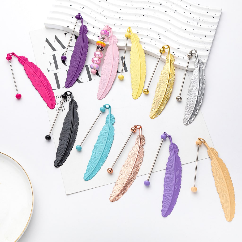 A collection of feather-shaped metal bookmarks in various colors attached to beads on strings.

