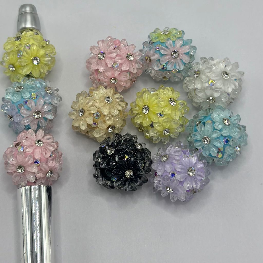 A collection of multicolored floral clay beads with clear rhinestone accents.


