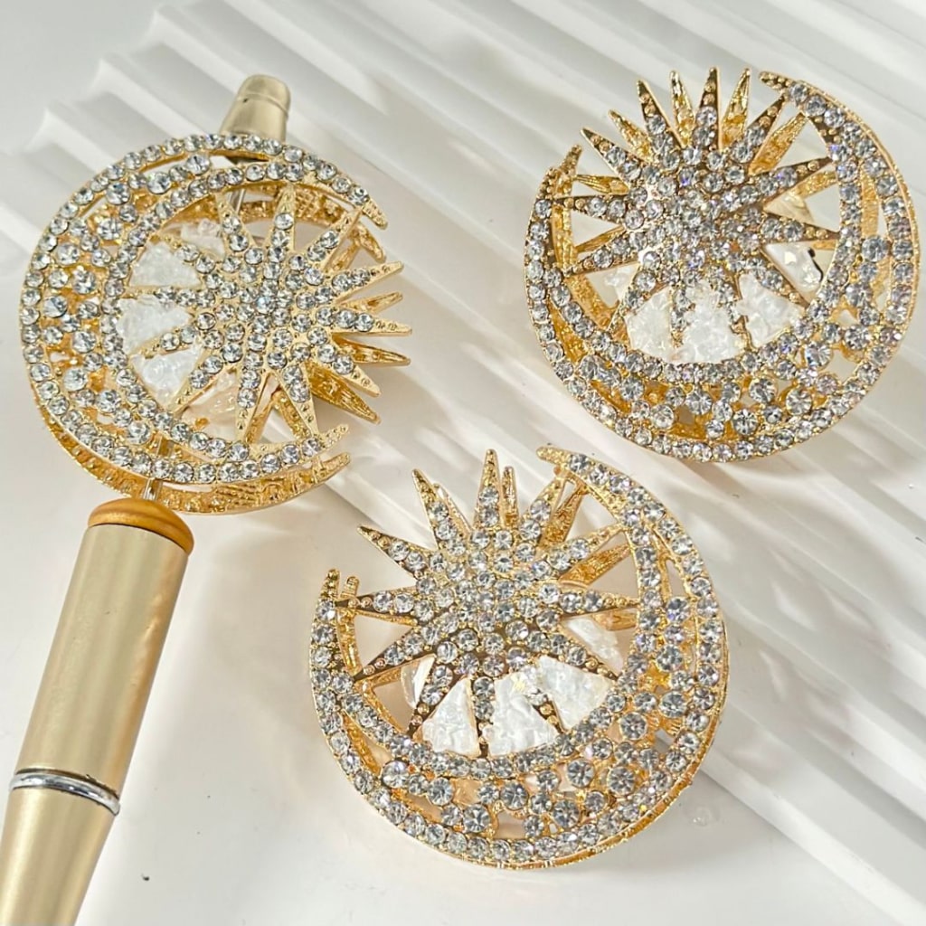 Gold alloy charms designed as crescent moons and suns, embellished with clear mini rhinestones and oval clear pearls, accompanied by clay beads.


