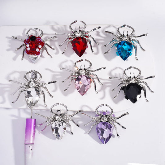 A collection of decorative spider-shaped brooches with various colorful rhinestones and small white pearls, displayed against a white background.

