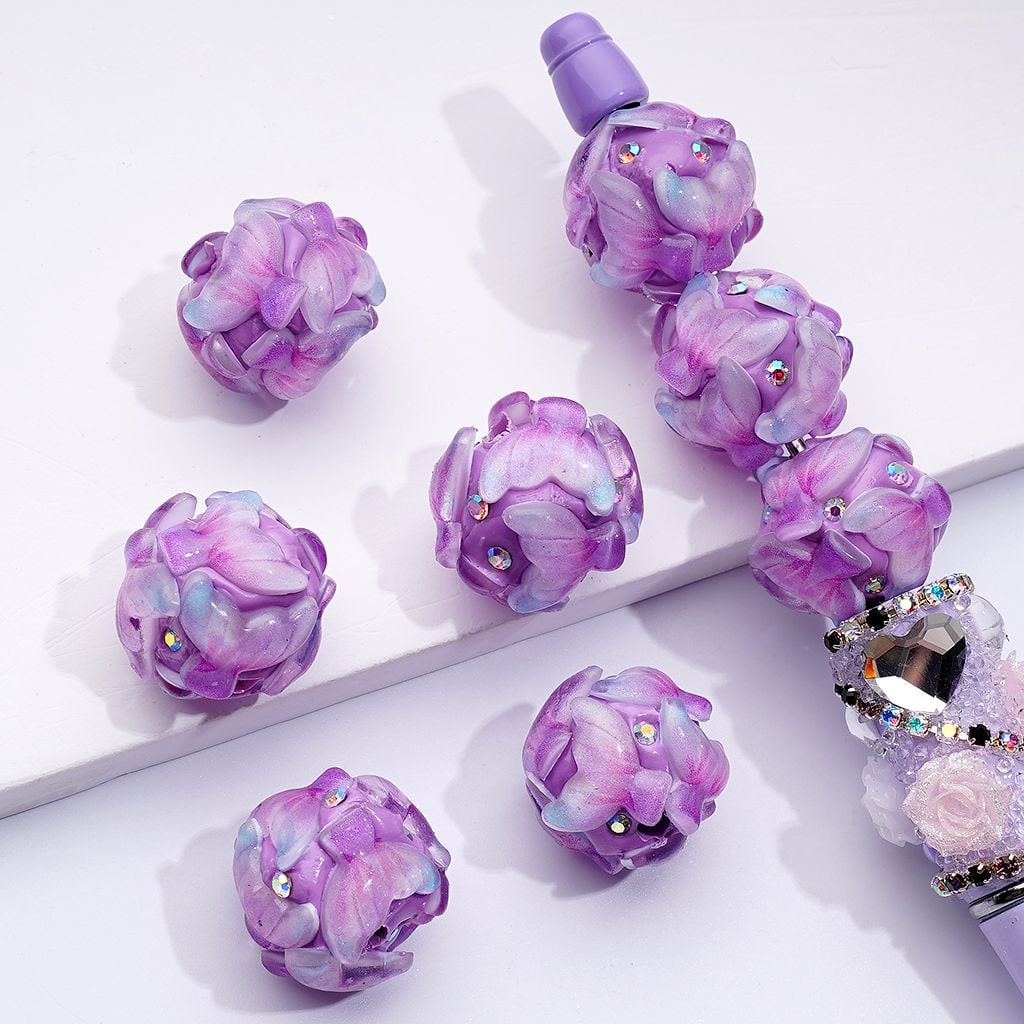 A collection of purple fish tail clay beads with AB rhinestones, approximately 20mm in size, displayed on a surface.

