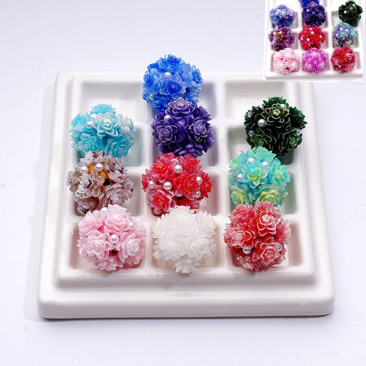 Colorful flower-shaped earrings on a white tray with a small inset showing more earrings.

