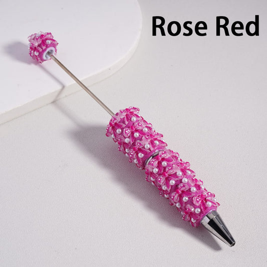 Decorative pen with pink bead embellishments on a light gray background

