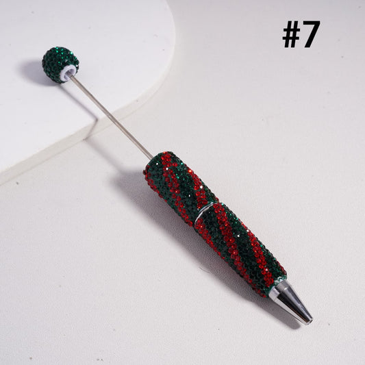 Decorative pen with red and green bead accents on a white background


