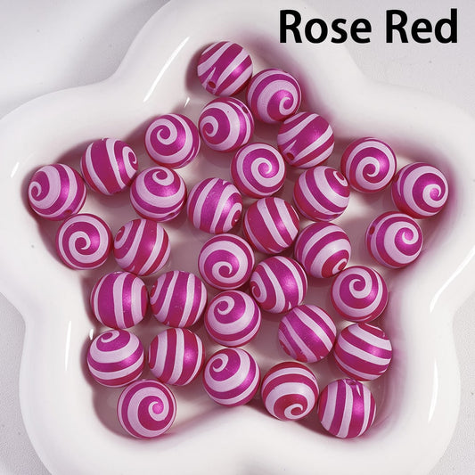 Rose red beads with white swirl patterns on a white plate

