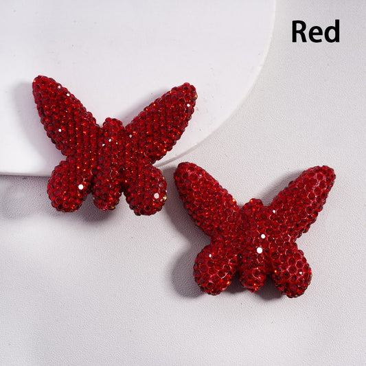 Red butterfly-shaped earrings on a light gray background

