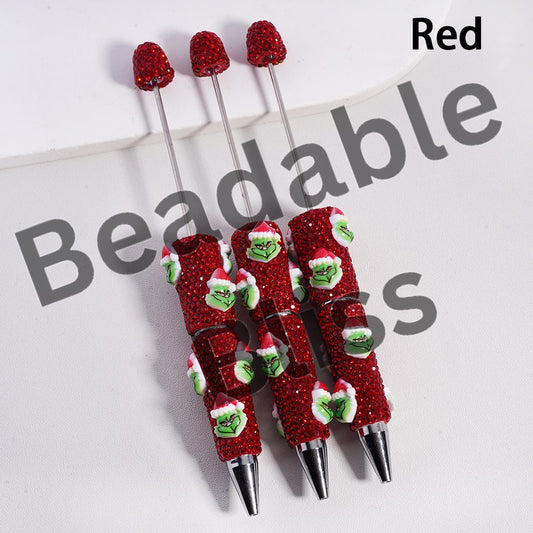 Set of red glittery pens with Grinch faces on a white background

