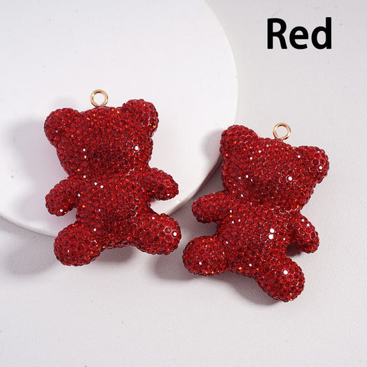 Red teddy bear-shaped earrings on a white plate with 'Red' text.

