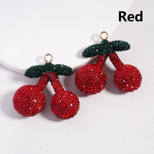 Cherry-shaped earrings with red and green details on a white background

