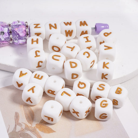 White letter beads with gold letters on a white surface