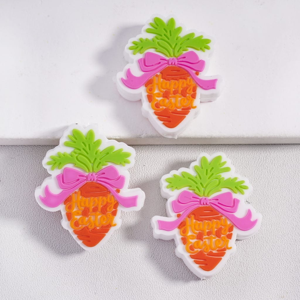 Three carrot-shaped 'Happy Easter' decorations with green leaves and pink bows on a white background.