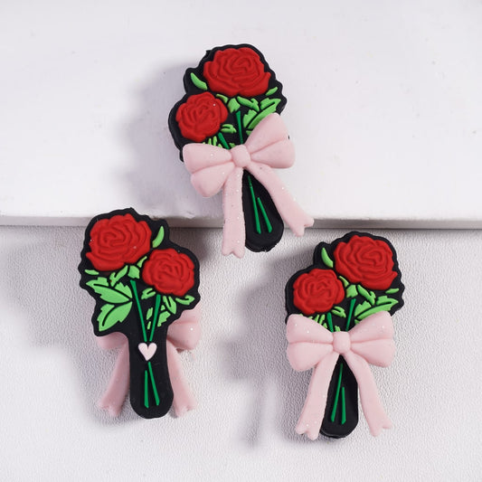 Three decorative hair clips with red roses and pink bows on a white background