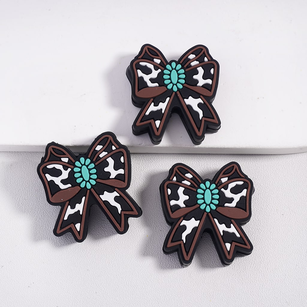 Three decorative bows with cow print and turquoise centers on a white background
