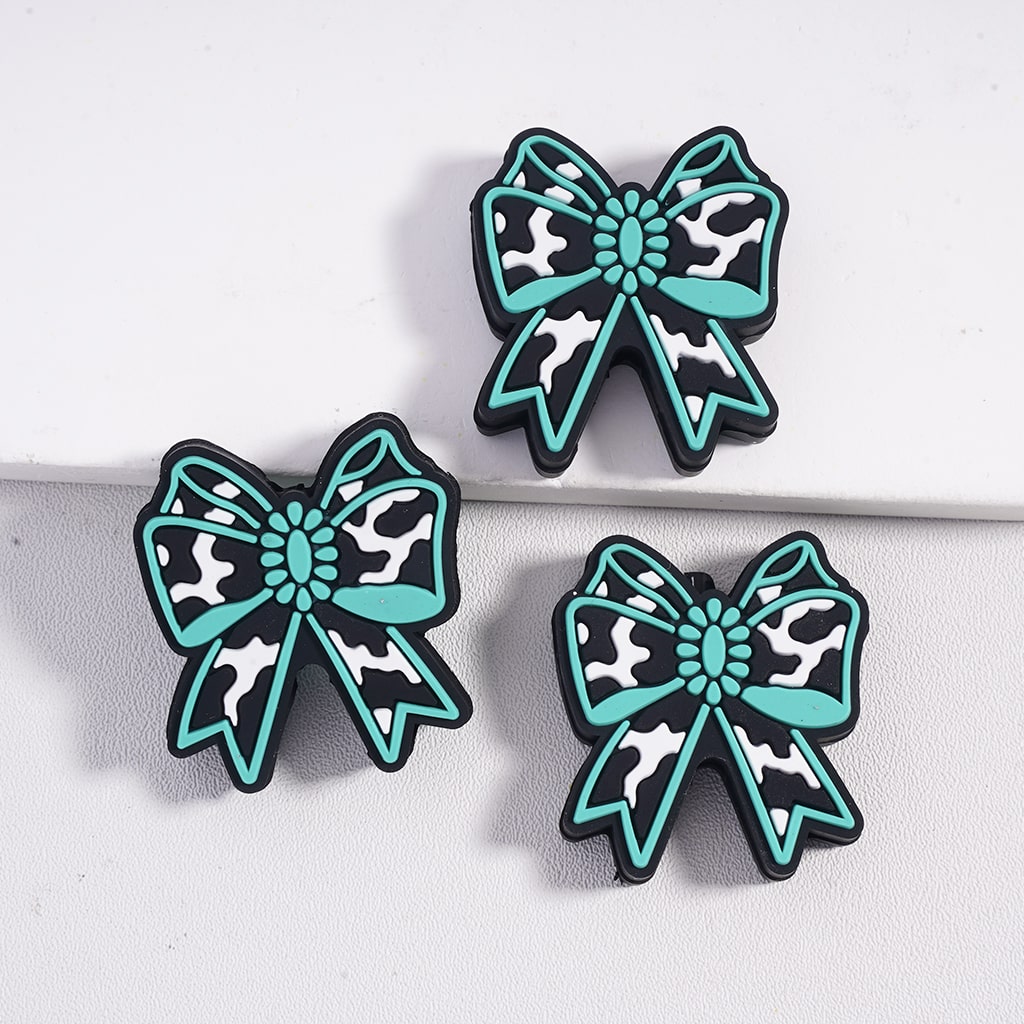 Three decorative bows with teal centers and black and white patterns on a light gray background

