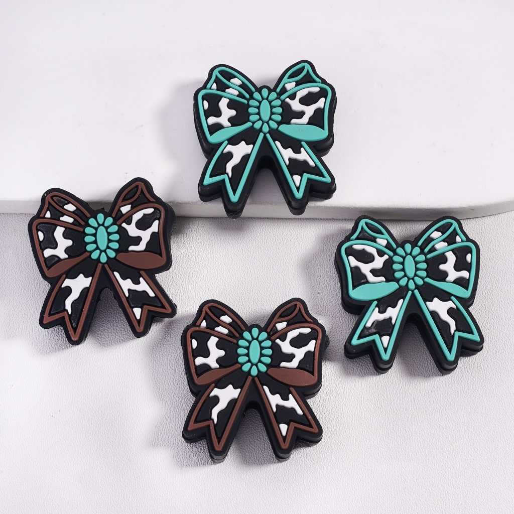 Four decorative bows with cow print pattern and teal centers on a white background
