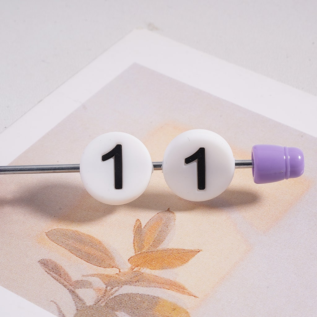 Pair of earrings with white beads displaying the number '1' on a light background.