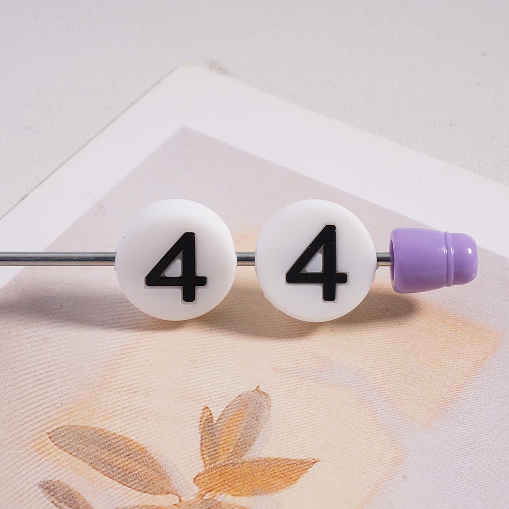 Belly button ring with '4' on white beads on a light background