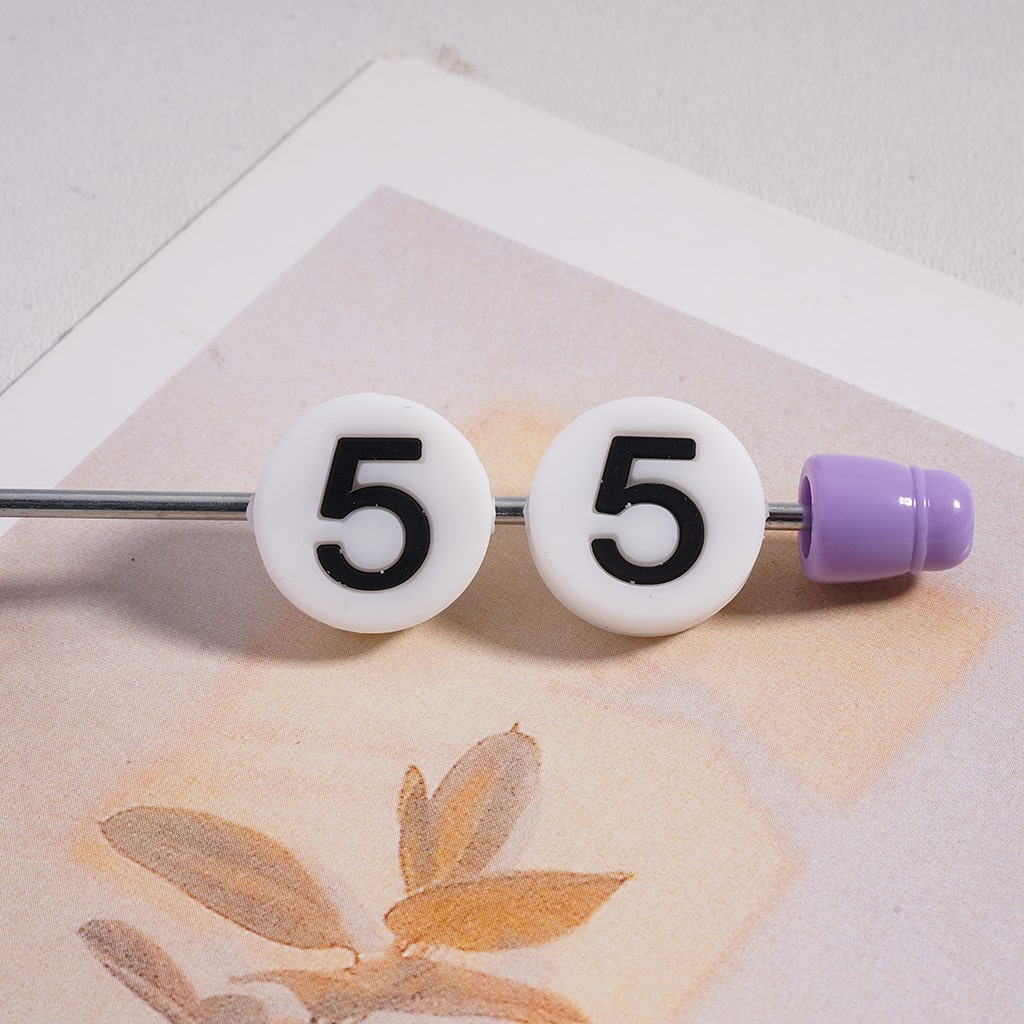 Belly button ring with white beads displaying the number 5 on a light background