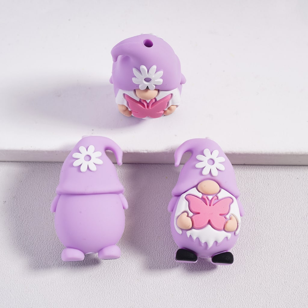 Three purple gnome-shaped charms with floral designs on a light gray background