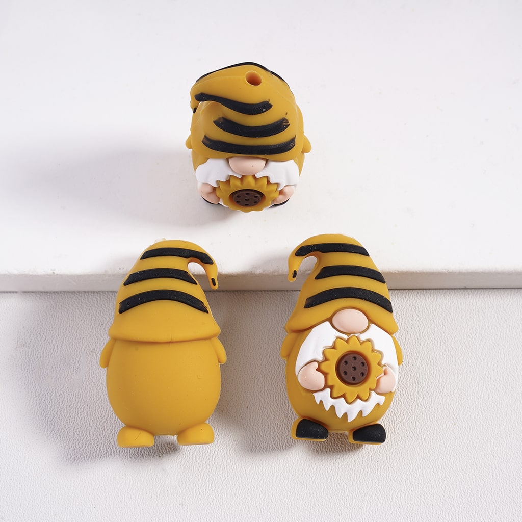 Three yellow and black striped gnome figurines with sunflower designs on a white background