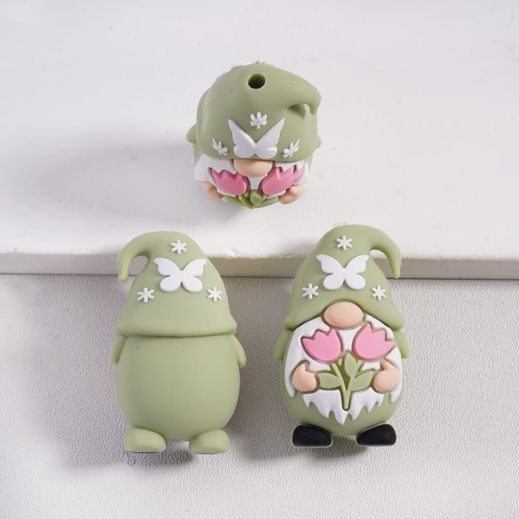 Three green gnome figurines with floral designs on a white background