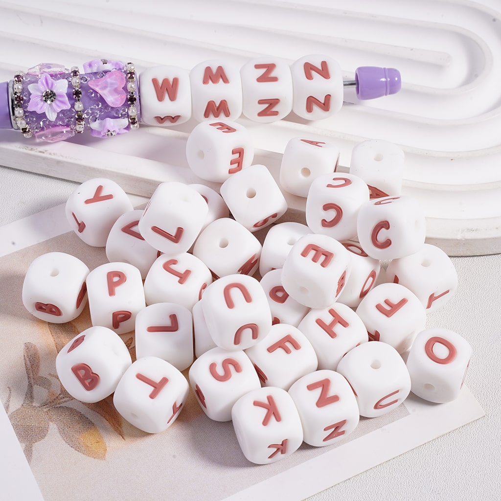 White beads with red letters and a purple tool on a white background