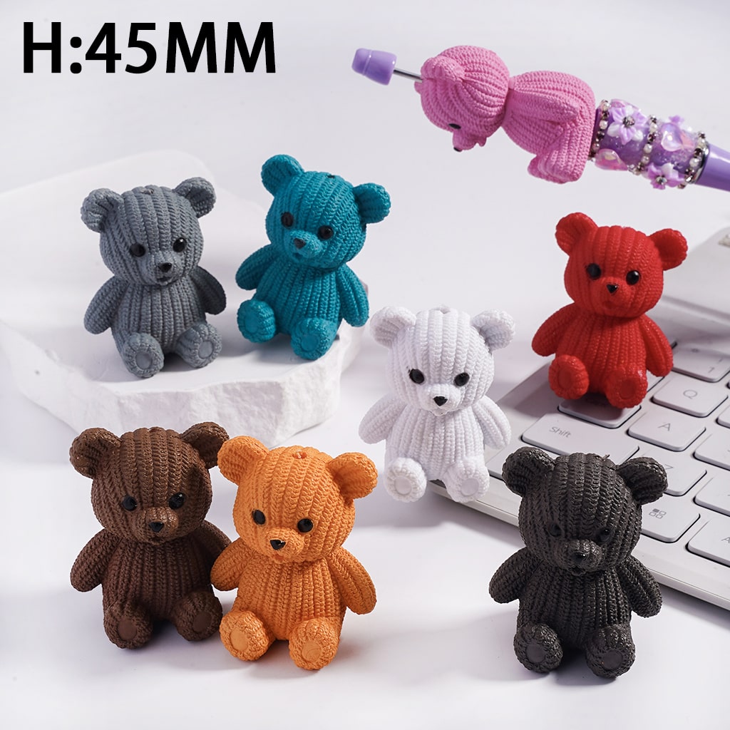 Small knitted teddy bears in various colors on a keyboard with a pink hair bow in the background.
