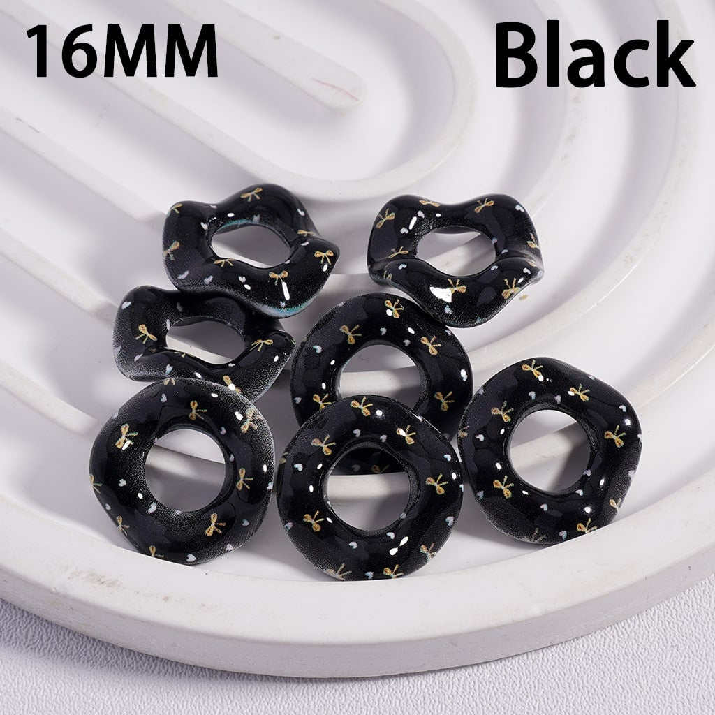 Black hair ties with gold bows on a white circular tray, labeled '16MM Black'.
