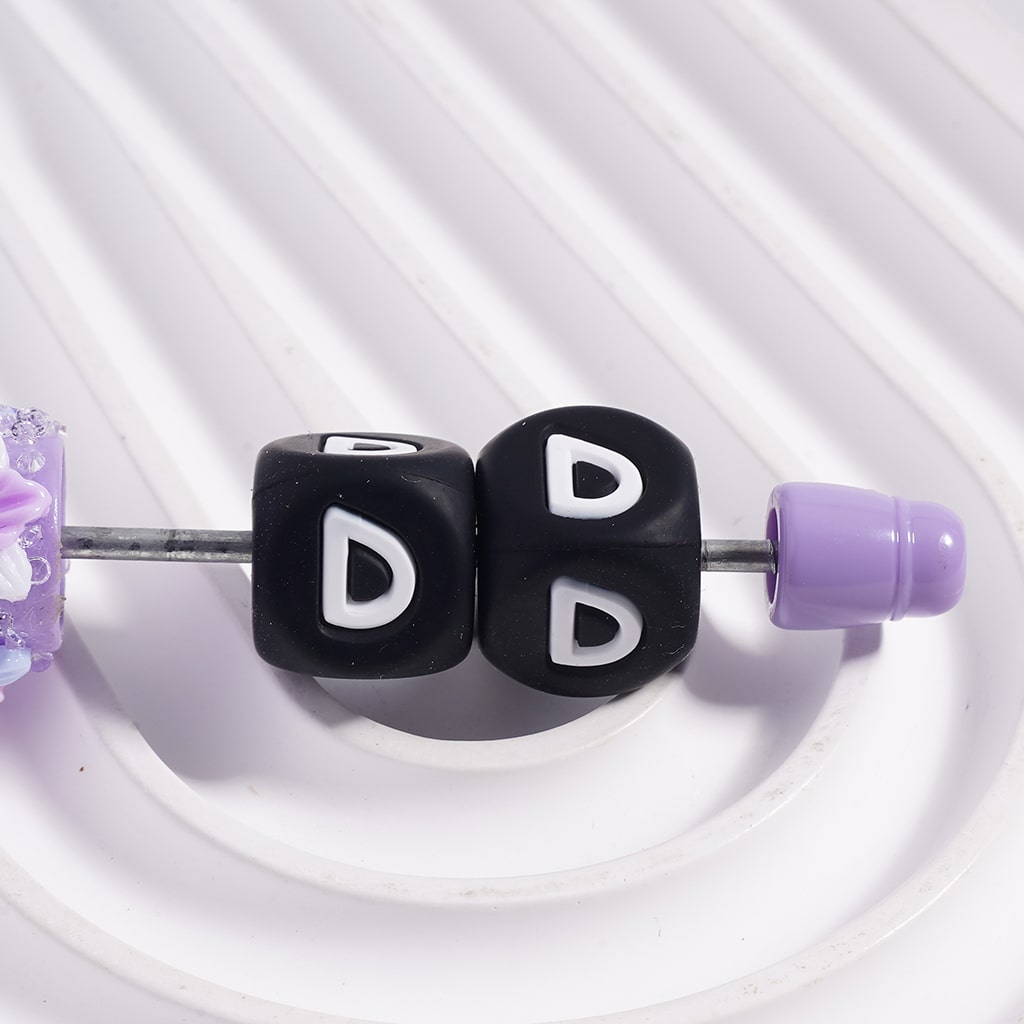 Close-up of a hair tie with black beads and purple ends on a white background