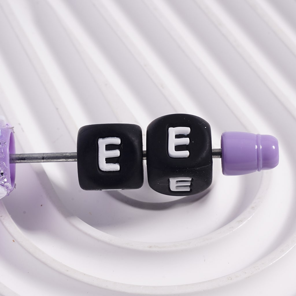 Black cube beads with 'EE' on a white background