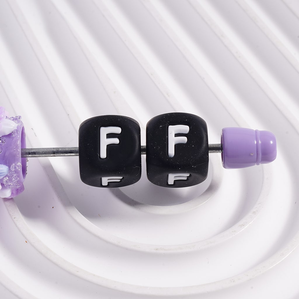 Black letter 'F' beads on a white background