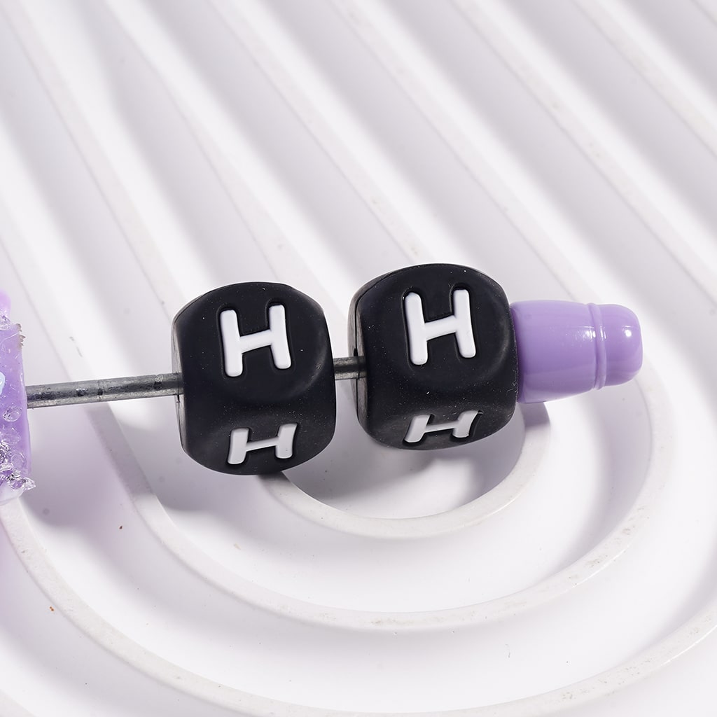 Close-up of earbud with 'H' labeled black tips on a white background