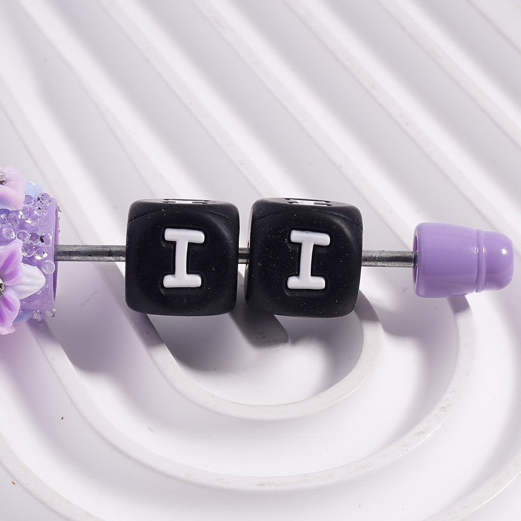 Belly button ring with black cube beads displaying 'II' and purple accents on a white background