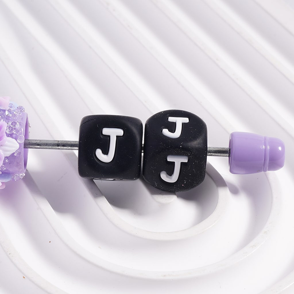 Belly button ring with 'J' beads on a white background