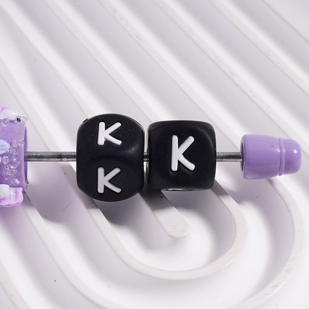 Beads with 'K' letters and purple ends on a white background